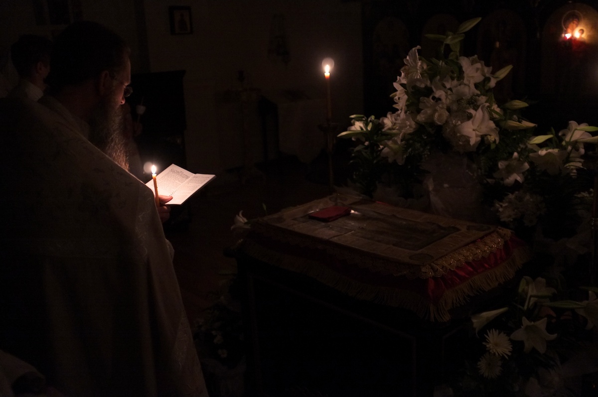 Orthodox priest reading at the tomb.